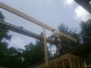 Carpenter setting a ridge beam over a new addition frame — Ice Dam Removal by Roofing Brothers in Proctor