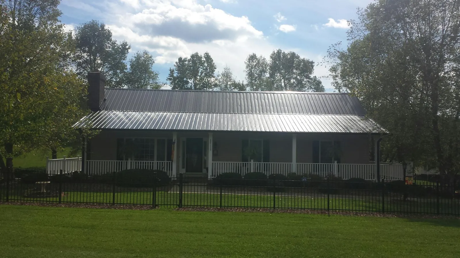 Gray metal roof on a brick ranch with a full width front porch — Gutter Guard Installation work by our crew in Proctor